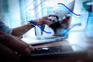 designer hand working and smart phone and laptop on wooden desk